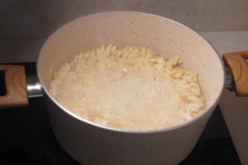 Cooking pasta in a pot on a stovetop in a modern kitchen setting