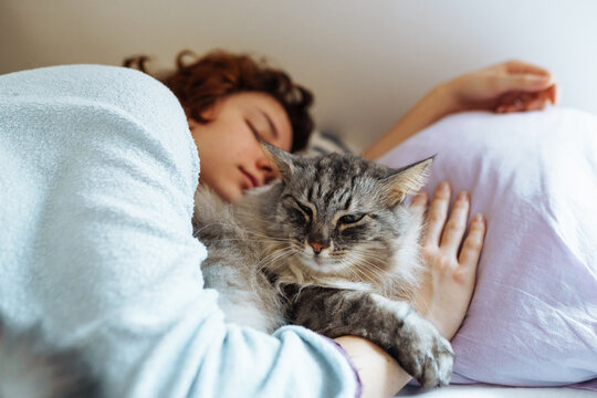 sleeping young woman on bed with pet cat