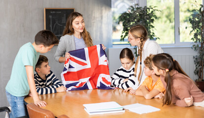 Teacher talking about her country and national flag of the Great Britain at Geography lesson. Positive Schoolchildren and female teacher discussing