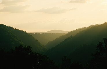 Obraz premium Golden hour landscape with rolling hills and soft pastel sky