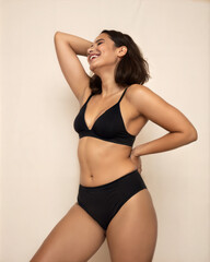 Woman Model with Ideal Body Shape Wearing Black Swimsuit in Beige Background Posing Confidently