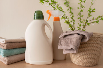 Eco natural household chemicals for home. Bottle with laundry detergent, folded bath towels and...