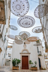 Crochet decorations on the narrow street of Locorotondo. Amazing view of the cozy Old town with plants in Locorotondo, Apulia Region, Italy
