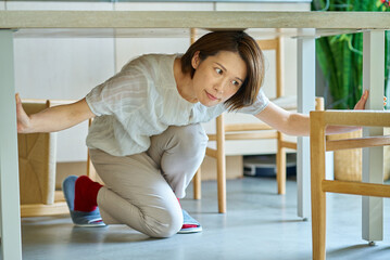 テーブルの下に隠れる女性