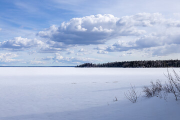 Large cloud hanging over frozen Waskesiu Lake in Prince Albert National Park, Canada