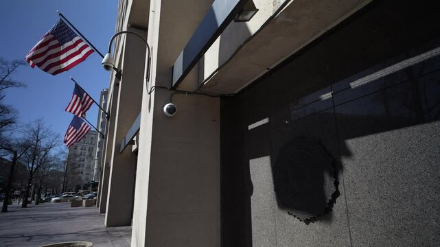The seal on front of J Edgar Hoover FBI headquarters building in Washington DC with flags on spring day.