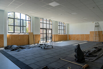 Salle de classe en cours de rénovation dans une école, avec matériel de chantier et murs partiellement refaits.