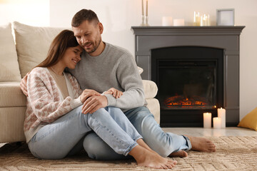 Happy couple sitting near fireplace on floor at home