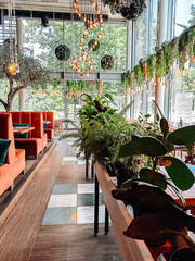 Restaurant with a lot of plants and a lot of seating