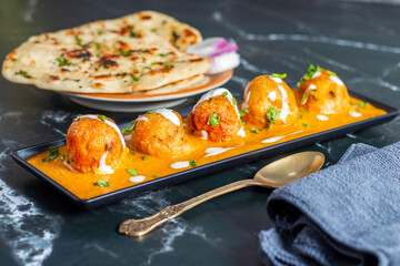Soft, creamy malai kofta in rich, spiced tomato-cashew gravy, perfectly paired with warm, fluffy butter naan—an indulgent North Indian delight bursting with flavour and aroma.