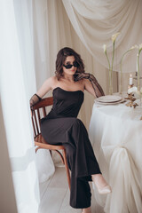 Stylish woman in sunglasses and black suit sitting