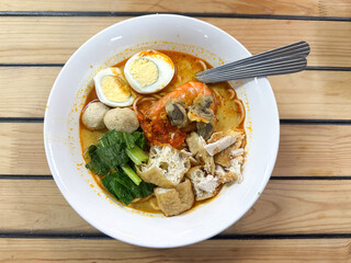 A bowl of curry noodles on wooden table.  Top view.
