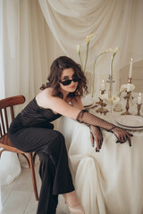 Pensive woman in black suit sitting on stool