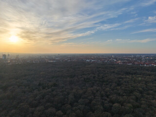 A scenic aerial view of a wooded area at sunset with an urban skyline in the background Hannover List Lower Saxony