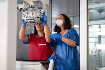 Two female radiographers preparing x-ray machine in hospital radiology department
