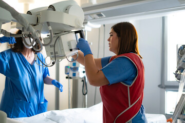 Healthcare professionals preparing x-ray machine in hospital room