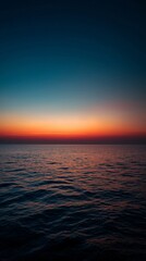 Obraz premium Ocean horizon at sunset with vibrant colors reflecting on the water.