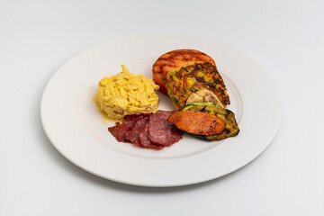 Rustic breakfast plate with fried eggs, grilled vegetables, and turkey bacon