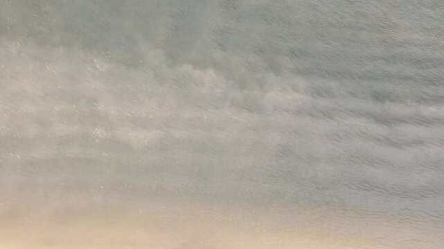 Drone image from a zenith angle of the water movement, which is a bit cloudy. The image has a slight camera movement, focusing on the water, which has slight waves.