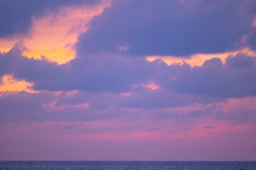 Vibrant sunset over tranquil sea in thailand with purple and orange sky