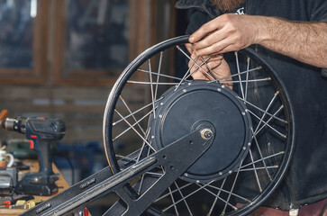 Bicycle mechanic disassembles wheel with an electric motor. Electric bicycle repair. Workshop.