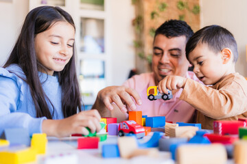 Happy father and children building with construction toys and toy cars, enjoying family time...