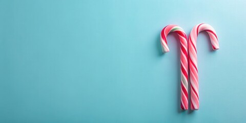 Pair of Peppermint Candy Canes on a Light Blue Background, a Festive Sweet Treat for a Holiday Celebration