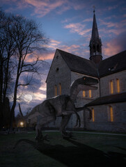 Ein Dinosaurier steht neben der Klosterkirche Loccum vom Mondlicht beleuchtet