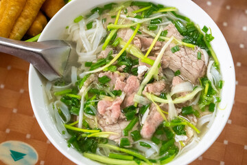 Close-up of sliced beef and green herbs in a hot bowl of pho bo, Hanoi, Vietnam on December 29, 2019