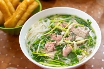A steaming bowl of phở bò is served with fried dough sticks at a casual eatery in Hanoi, Vietnam on December 29, 2019