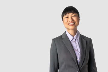 Portrait of beautiful and confident business woman. Happy Asian businesswoman smiling on grey wall.