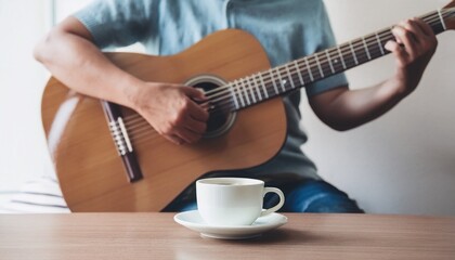 A cup of coffee and hands playing a guitar