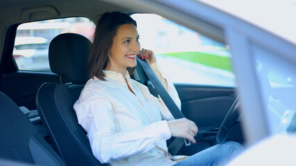 Smiling businesswoman fastening her seat belt while sitting in her car