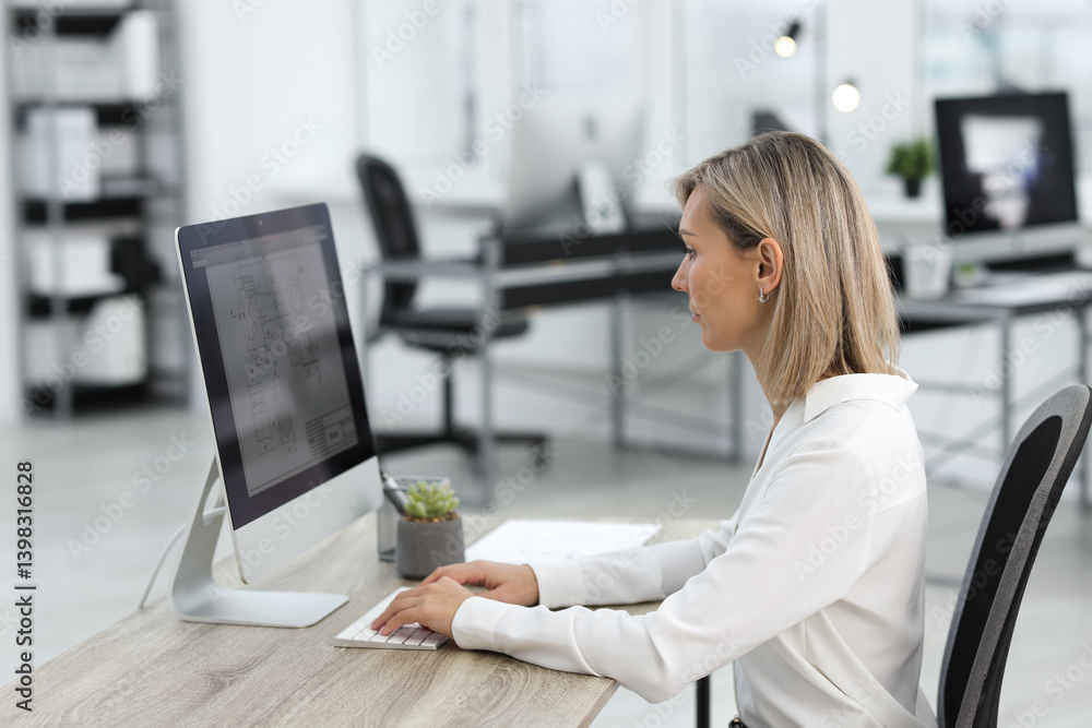 Poster technician making digital engineering drawing on computer at desk in office