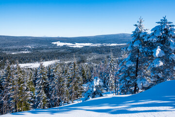 Breathtaking view to the nordic like landscape of Jizera river with deep snow covered forest and meadows hidden in the mountain valley during beautiful sunny winter day, Czechia