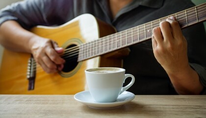 Fototapeta premium A cup of coffee and hands playing a guitar