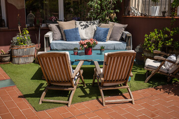 Cozy outdoor seating area with a distressed blue table, soft pillows, and green surroundings