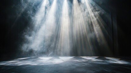 An empty stage with beams of white light cutting through a smoky atmosphere.