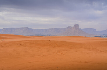 A panoramic view of vibrant Red Sand dunes in Saudi desert, capturing a dynamic desert landscape under clear blue skies.
