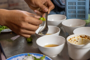 A vendor prepares bowls of dipping sauces and fresh herbs for banh cuon at a Hanoi food stall on December 29, 2019