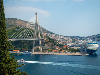 Obraz premium View of Dubrovnik harbor with Franjo-Tuđman Bridge suspended in the Adriatic Sea. Panoramic viewpoint where you can admire the scenery of the cruise ships and the bridge
