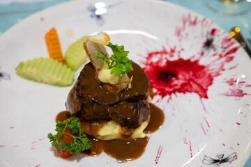 An elegant beef medallion dish is plated with mashed potatoes, carrots, and artistic beet sauce splashes in Ha Long Bay, Vietnam on December 27, 2019