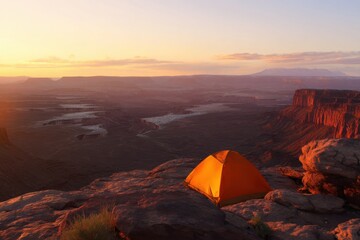 Camping at sunset overlooking a vast canyon with a river winding through the valley.