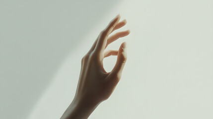 A subtly lit, elegant close-up of a woman's hand reaching towards the light.  The image is minimalist and evokes a sense of serenity and grace.
