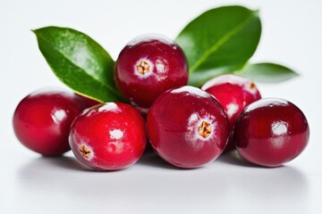Obraz premium A group of cranberries with green leaves on a white surface seen close isolated on white background