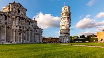 Scenic view of Piazza dei Miracoli in Pisa, Italy, with the Leaning Tower, Baptistery, and Cathedral. The green lawn contrasts with the white marble architecture of this UNESCO site.