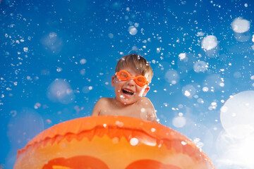 Happy child playing in waterpark. Kid having fun on summer vacation