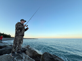 Young happy woman and old man is fishing at sea during spring vacation