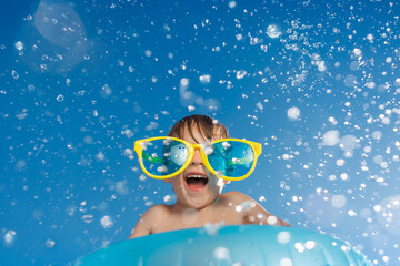 Happy child playing in waterpark. Kid having fun on summer vacation