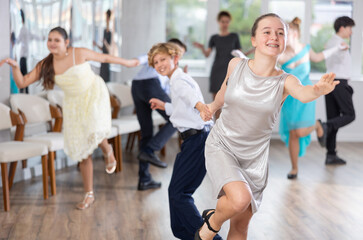 Obraz premium Happy teenage boys and beautiful girls dance a fiery twist dance